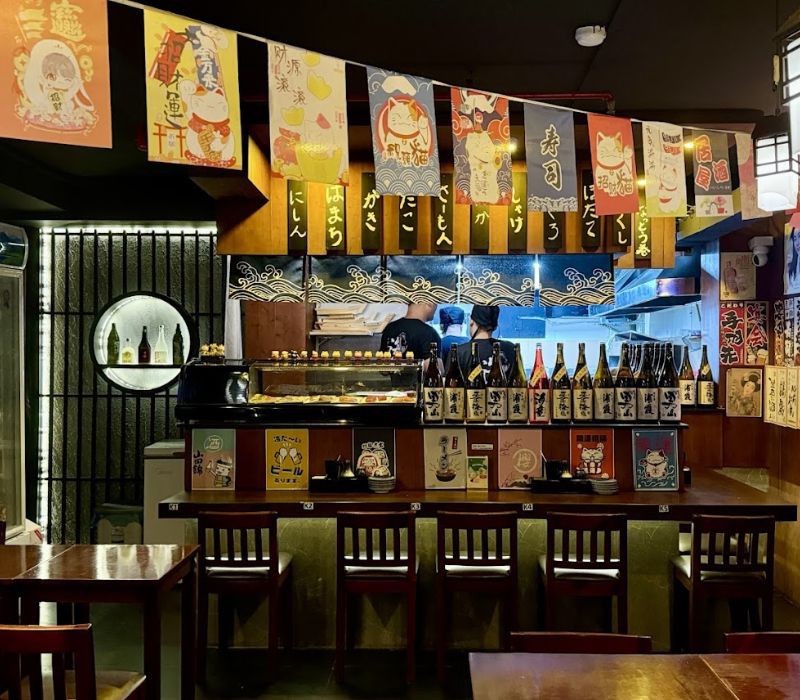 Góc bếp mở tại Izakaya MIE, thực khách có thể quan sát đầu bếp chế biến món ăn. Không gian quán ấm cúng với ánh đèn vàng tạo cảm giác thư giãn.